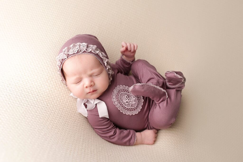 Baby girl wearing a purple sleeper and matching bonnet