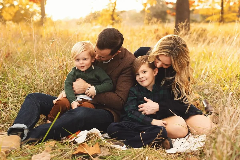 Family snuggling under a tree during a fall outdoor photo session in Kansas City