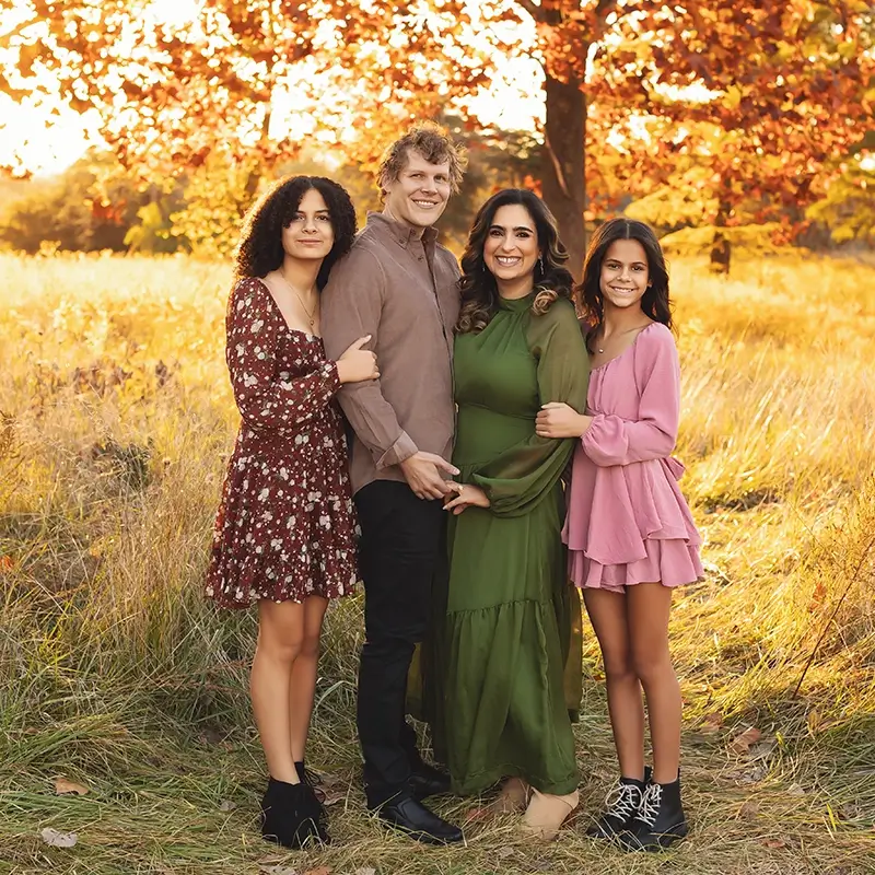 Fall-family-portraits-golden-hour-kansas-city family of four fall portraits in Kansas City with colorful autumn leaves, wearing coordinated burgundy, green, and pink outfits