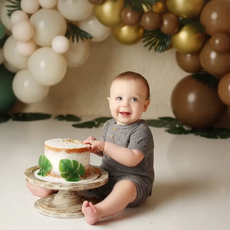 Kansas-city-cake-smash-jungle-them-studio-session First birthday cake smash with gold and green balloon backdrop in Kansas City studio, testimonial from Kelly