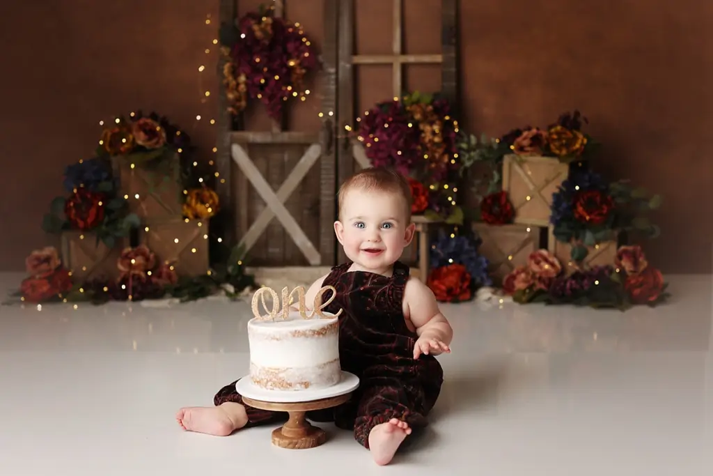 Baby girl enjoying fall floral themed cake during custom cake smash session in Kansas City