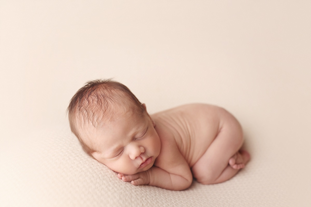 Newborn baby boy posed on soft neutral blanket during stress-free newborn photography in Kansas City