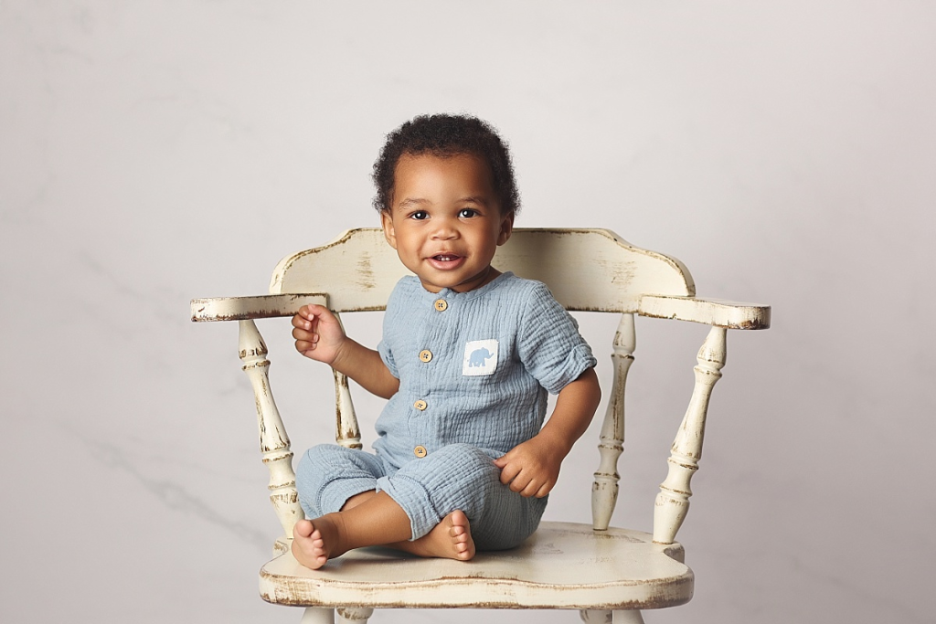 Professional portrait of baby boy seated in themed chair during first birthday session