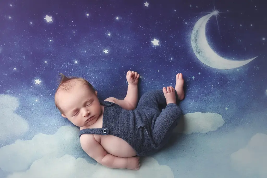 Newborn baby boy posed on moon and stars fabric in professional newborn portrait