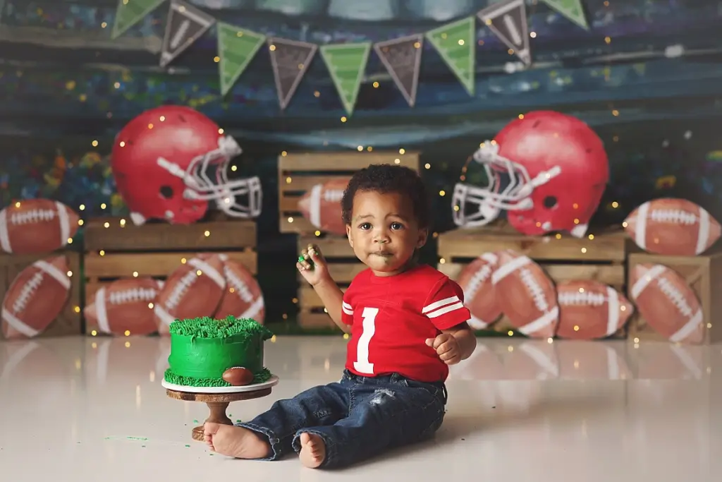 Messy cake smash portrait of baby boy with football cake during First Down theme