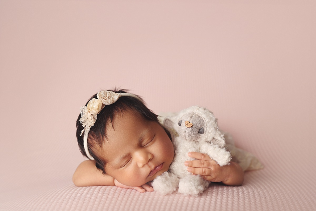 Sleeping baby girl posed on soft pink fabric at Anna Marie Photography studio