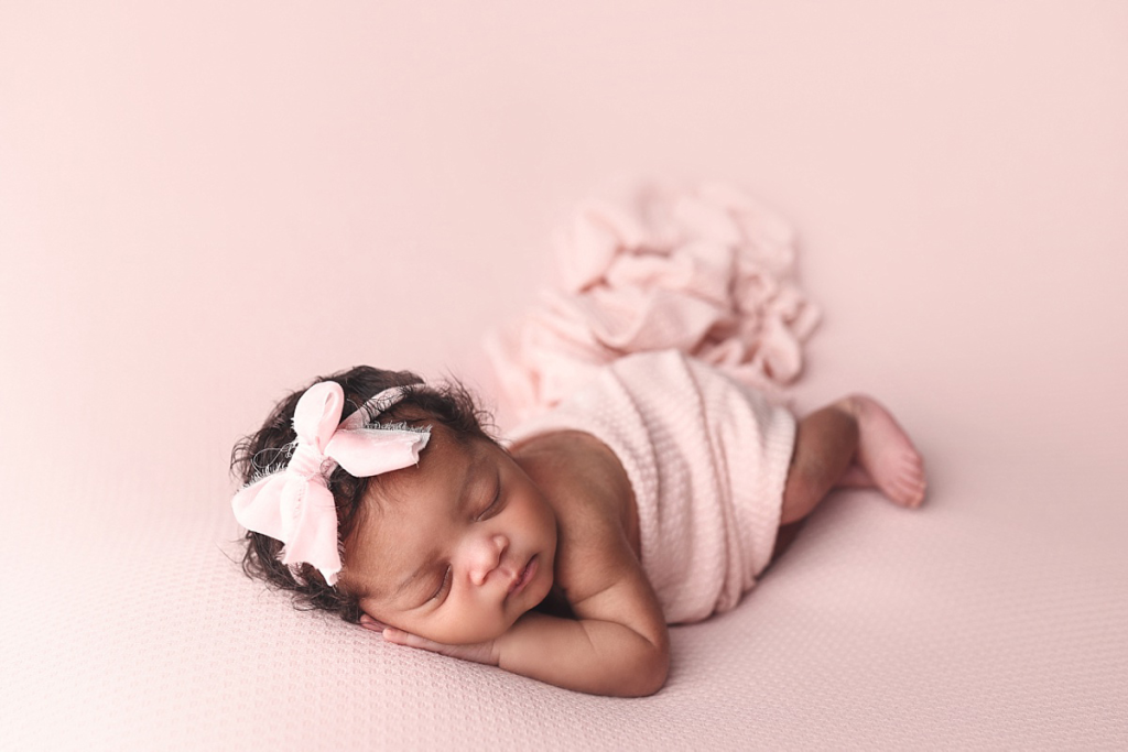 Newborn baby girl lying on textured pink blanket at Anna Marie Photography studio