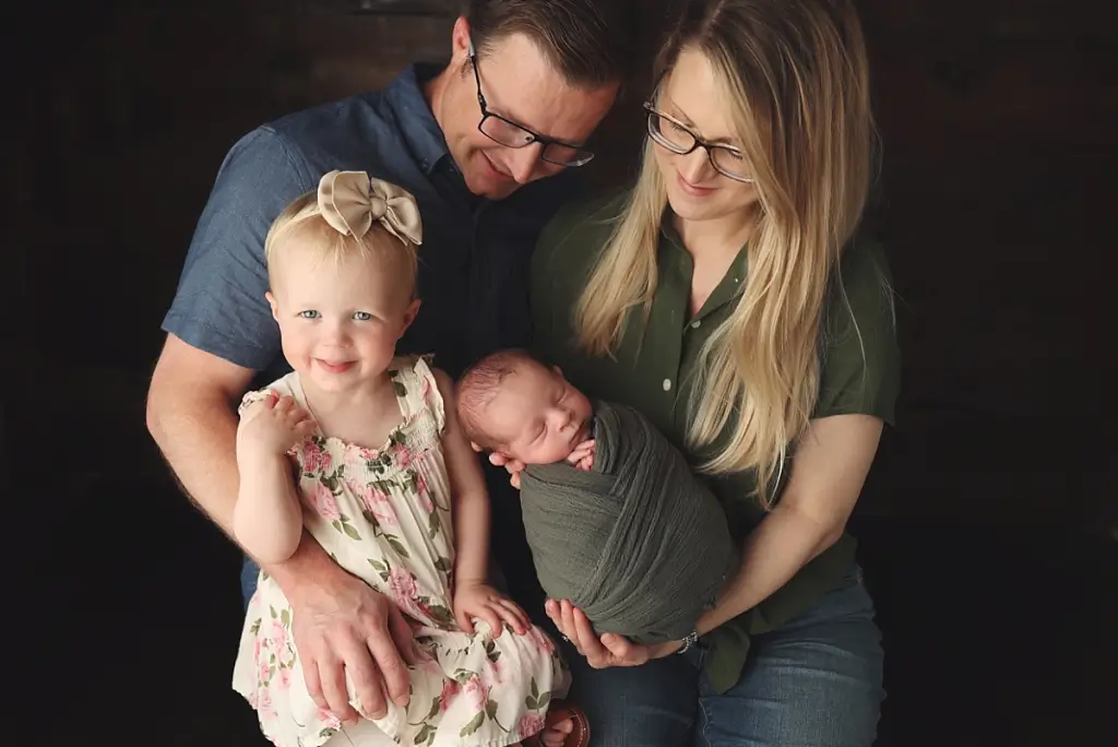 Parents and siblings posing with newborn baby boy in cozy family portrait