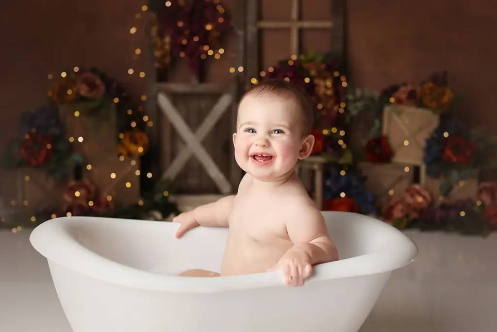 Smiling baby girl in bubbly bath cleanup at end of cake smash session