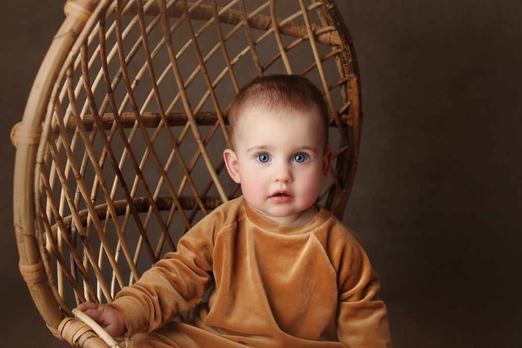 Baby girl posed in wicker chair during stress-free first birthday session