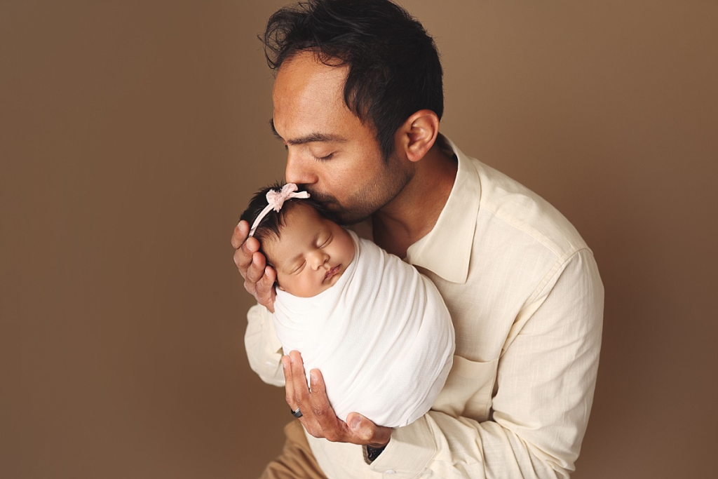 Father cradling newborn baby girl in timeless Kansas City family portrait