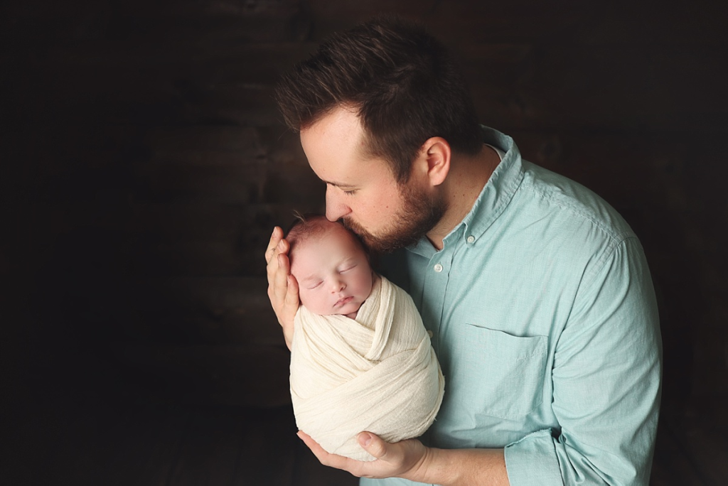Father holding newborn baby boy in timeless Kansas City newborn portrait