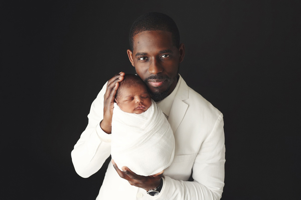 Father holding newborn baby boy during professional Kansas City newborn portraits