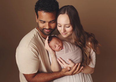 A mom and dad snuggle their newborn son in a Kansas City studio newborn session.