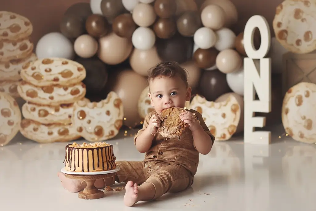 One-year-old boy sitting with chocolate chip cookie themed cake during Kansas City cake smash session