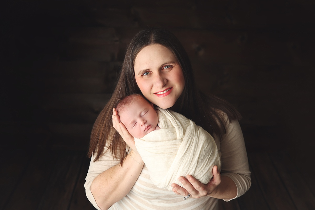 Mother cradling newborn baby boy during professional newborn photography session