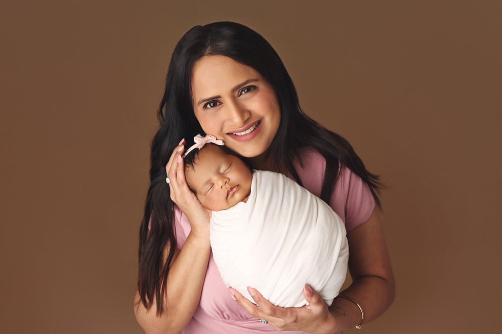 Mother gazing at newborn baby girl during cozy newborn and family photography session