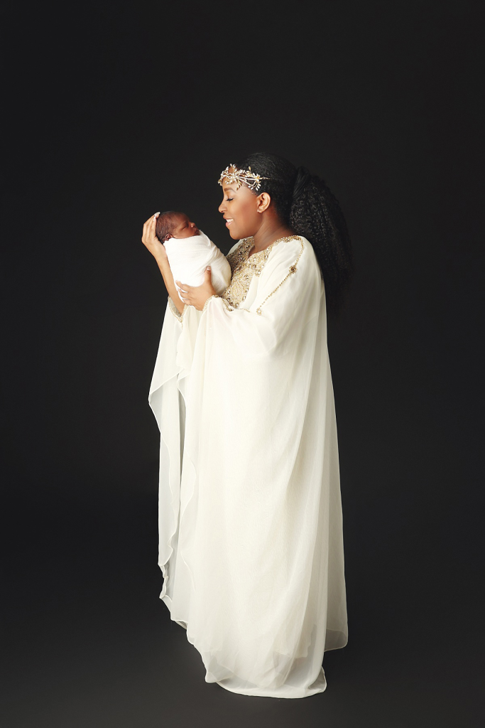 Mom snuggling newborn son wrapped in soft fabric at Anna Marie Photography studio