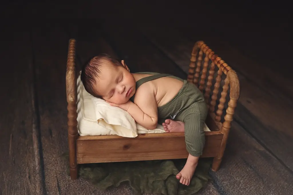 Baby boy posed on tiny bed during Kansas City newborn photography session