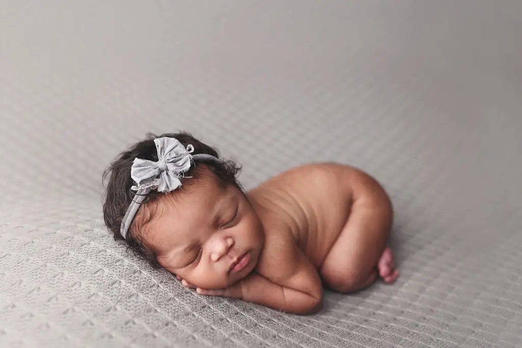 Sleeping newborn girl posed on textured fabric at Anna Marie Photography studio in Kansas City