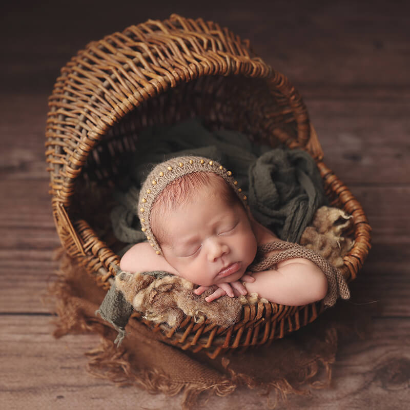 newborn-boy-posed-in-cradle-shaped-basket-kc-studio-session Baby boy in basket with his chin resting on his hands during his Kansas City studio newborn session
