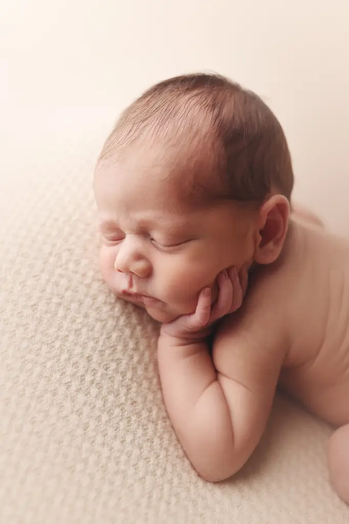Close-up of newborn baby boy’s face on neutral fabric during professional portraits