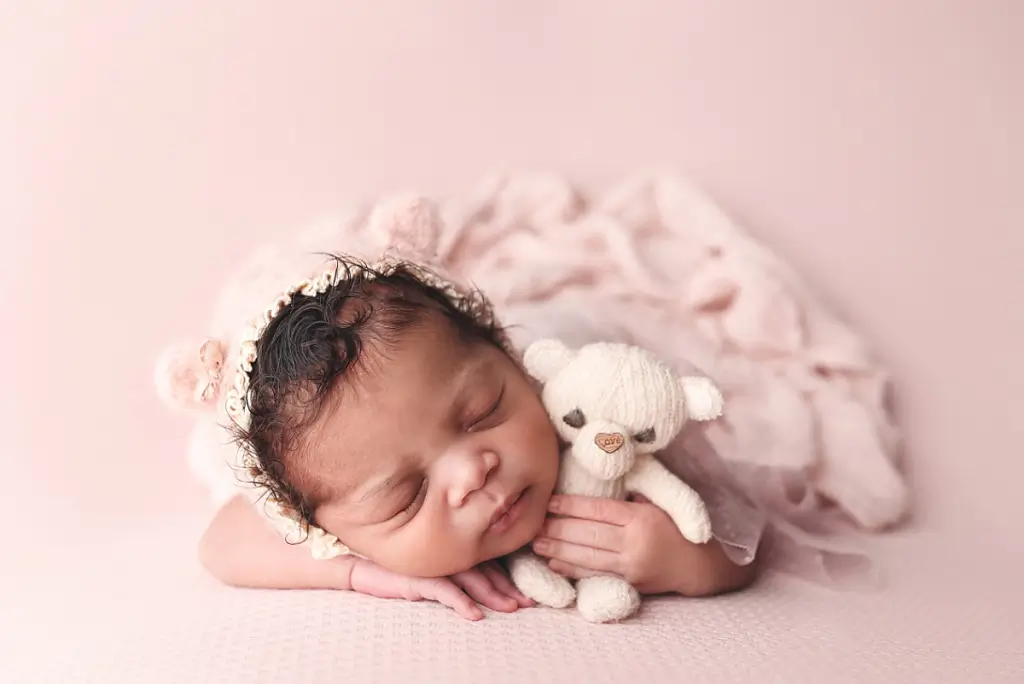 Sleeping baby girl in cozy pose with soft lighting during professional newborn photo session