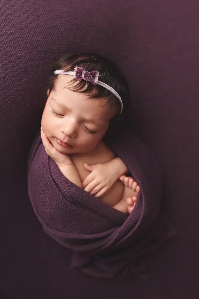 Newborn girl posed on textured blanket in cozy Kansas City photography studio