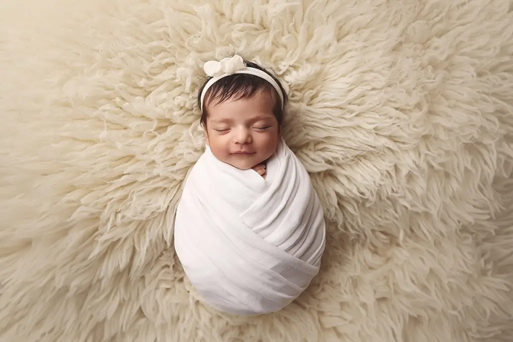 Baby girl posed on cozy fabric backdrop during Kansas City newborn portraits
