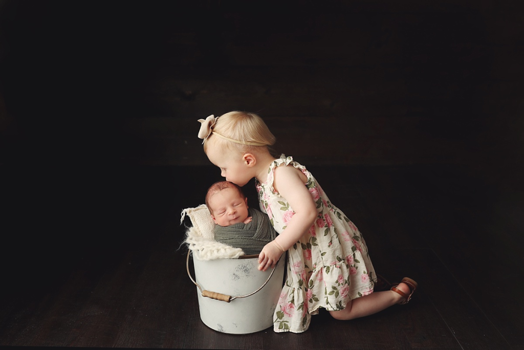 Big sister kissing newborn baby brother during Kansas City newborn photography session
