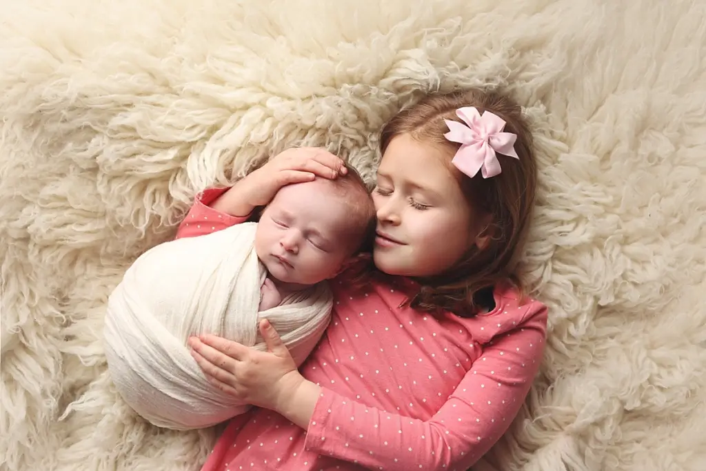 Big sister cuddling newborn baby brother during Kansas City newborn photography session