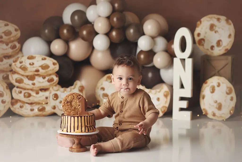 Smiling baby boy enjoying chocolate chip cookie cake smash portraits in Kansas City