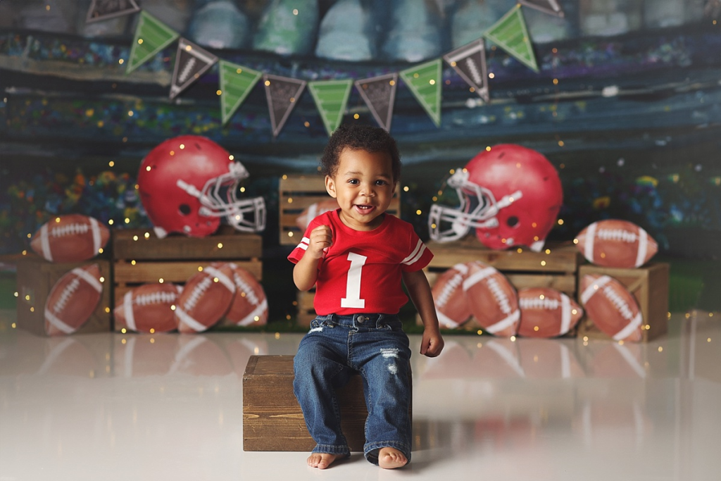 Baby boy sitting on football themed set during First Down cake smash session in Kansas City