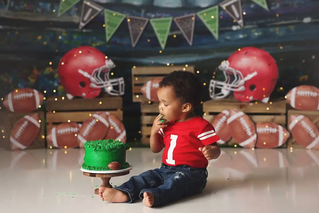 Baby boy enjoying football themed cake during Kansas City cake smash photography session