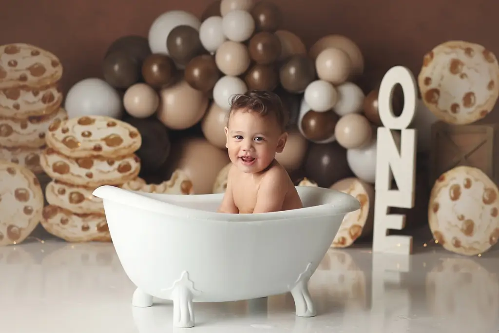 One-year-old boy splashing in bubble bath after Kansas City cake smash photography session