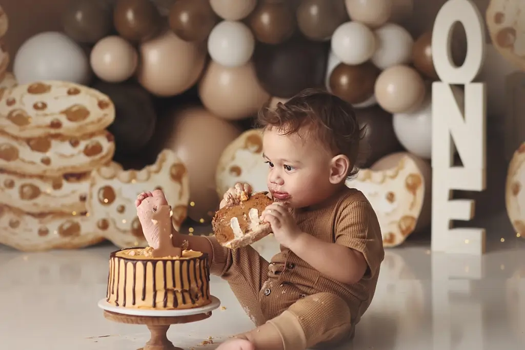 Baby boy smashing chocolate chip cookie themed cake during stress-free Kansas City cake smash photography session