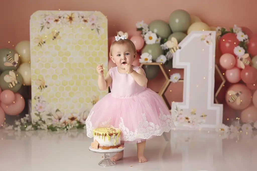 One-year-old girl smiling during honeybee themed cake smash photo session