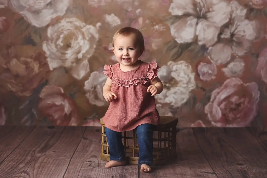 Baby girl sitting on wooden crate during Kansas City first birthday photography session