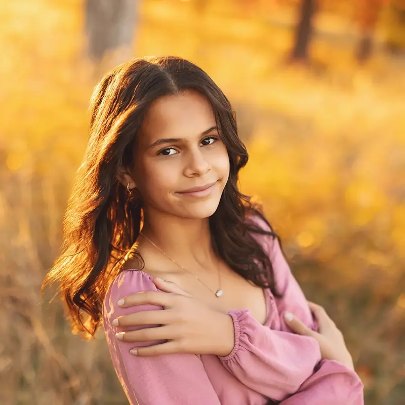 outdoor-family-fall-session-kansas-city Teen girl outdoor portrait in light pink dress with long curled hair, smiling in golden field during fall sunset session