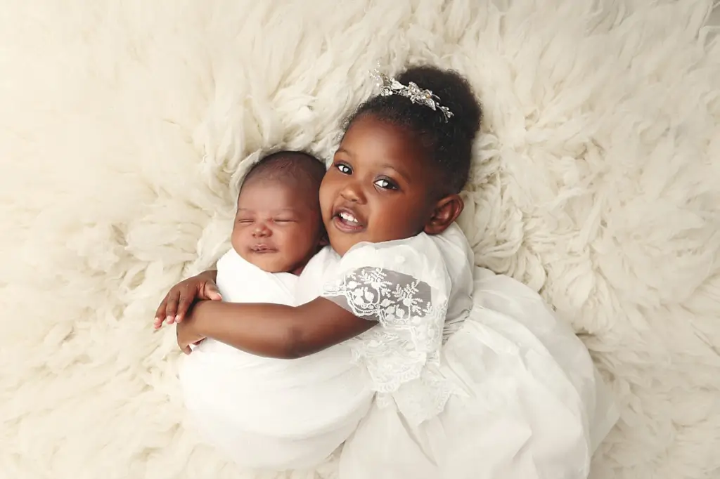 Big sister holding newborn baby brother during Kansas City newborn photography session