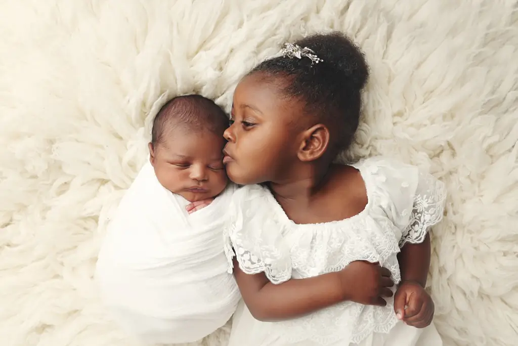 Sibling portrait of young girl cuddling baby brother at Anna Marie Photography studio