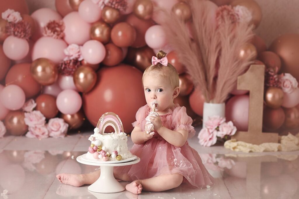 baby girl at kansas city cake smash session celebrating her first birthday with pink and gold shoot