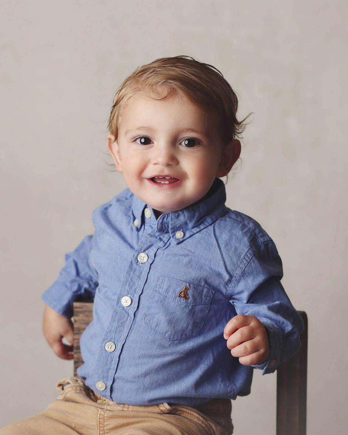Close4 up milestone portrait of a one year old boy wearing a bule button up shirt