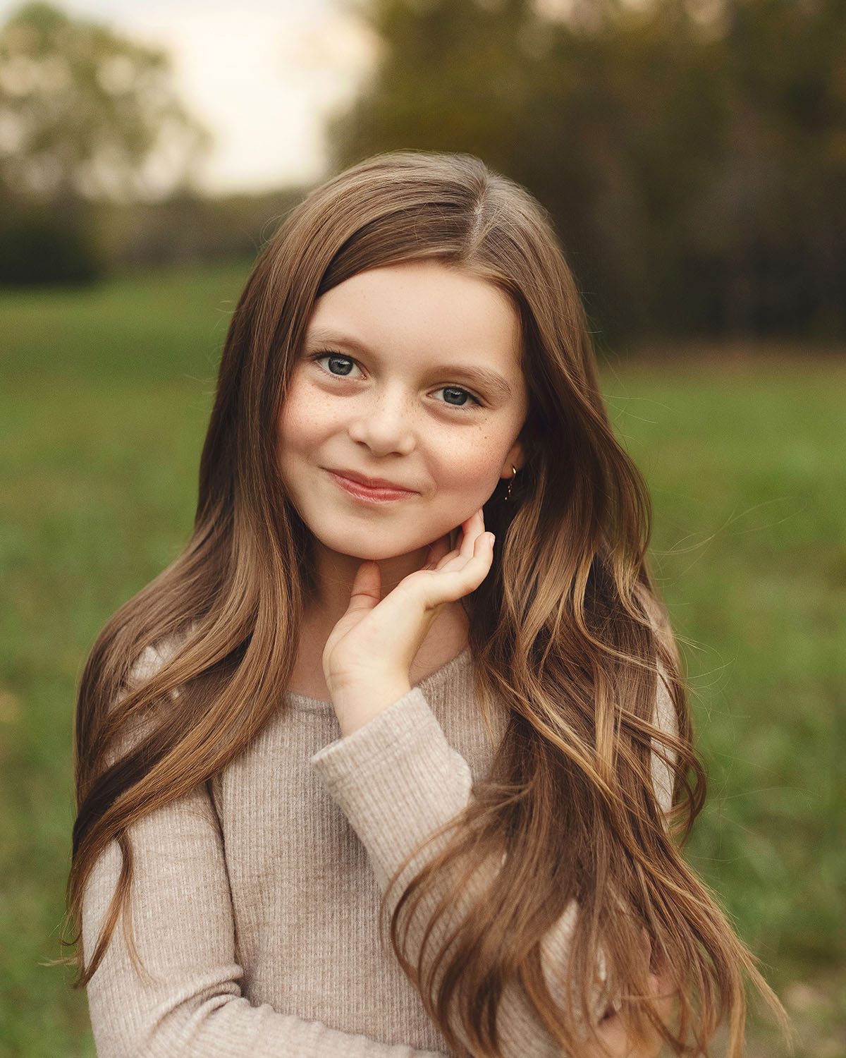 Outdoor portrait of a smiling young girl with long brown hair and photographed in natural light