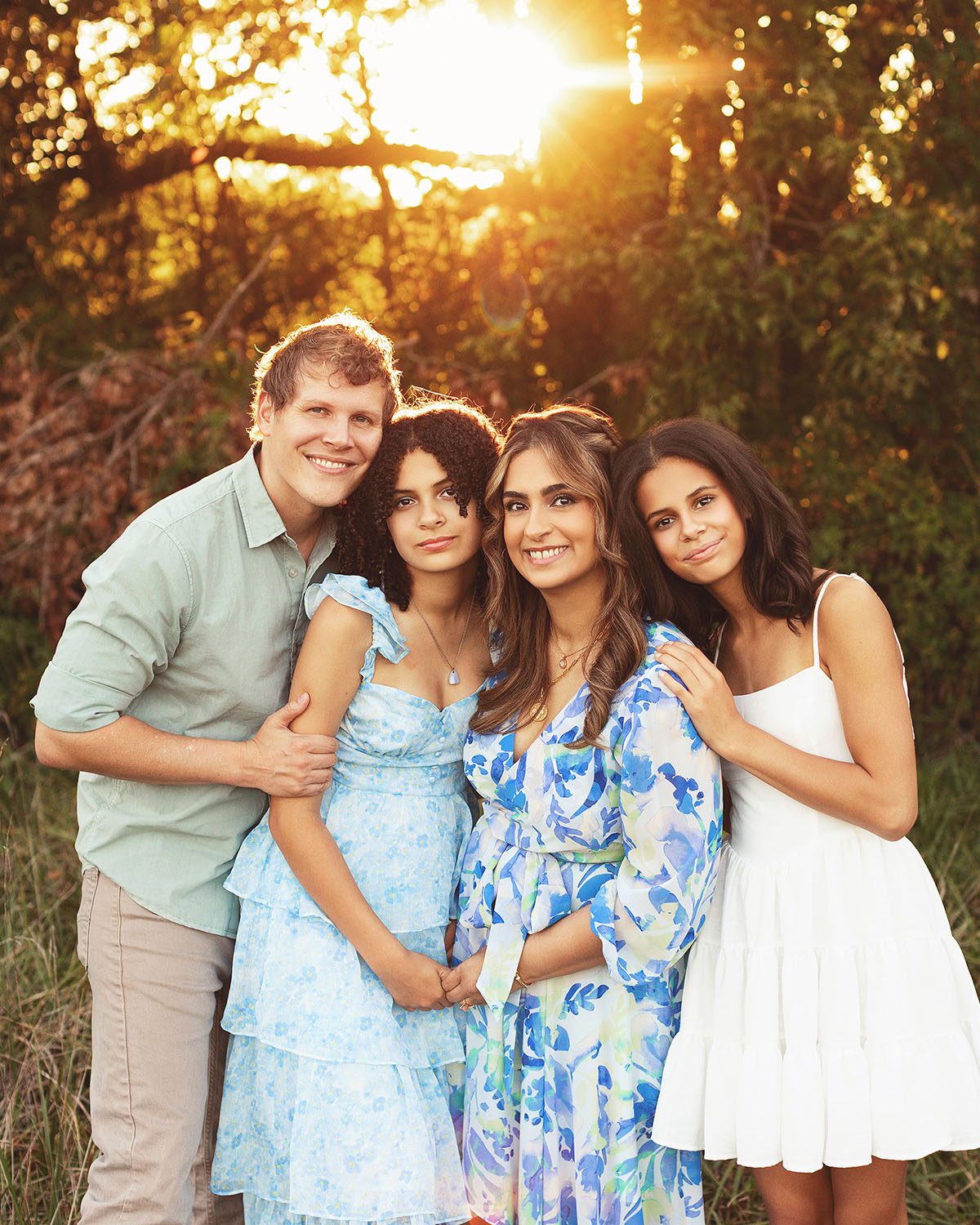 Outdoor family portrait at golden hour with backlit sunlight showing a mother, father, and two daughters during a fall family photography session.