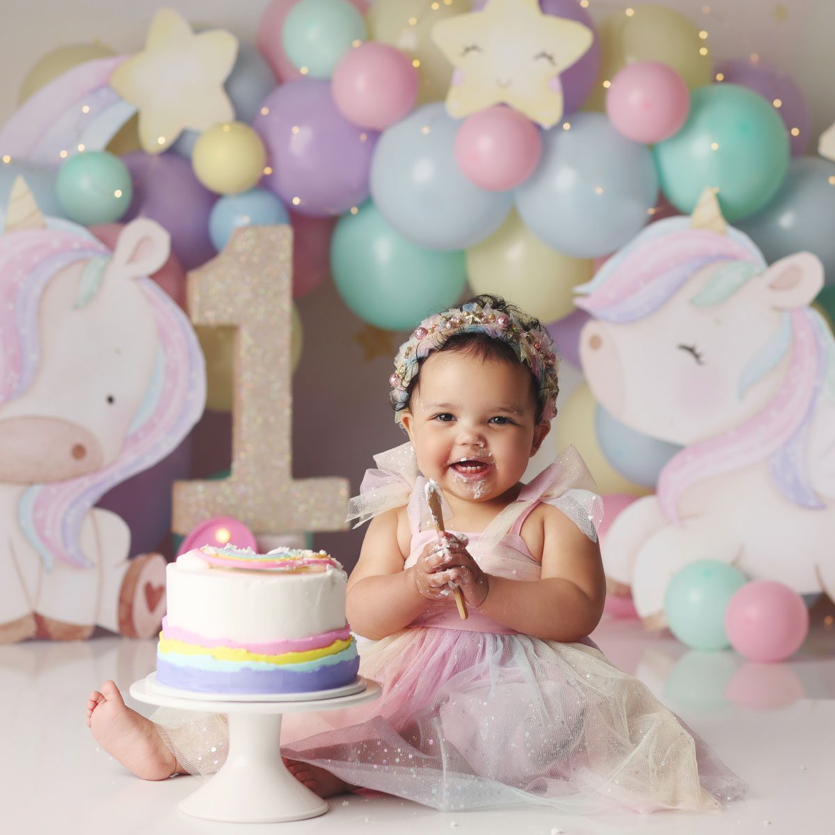 Little girl unicorn theme cake smash with rainbow striped cake in Kansas City Studio
