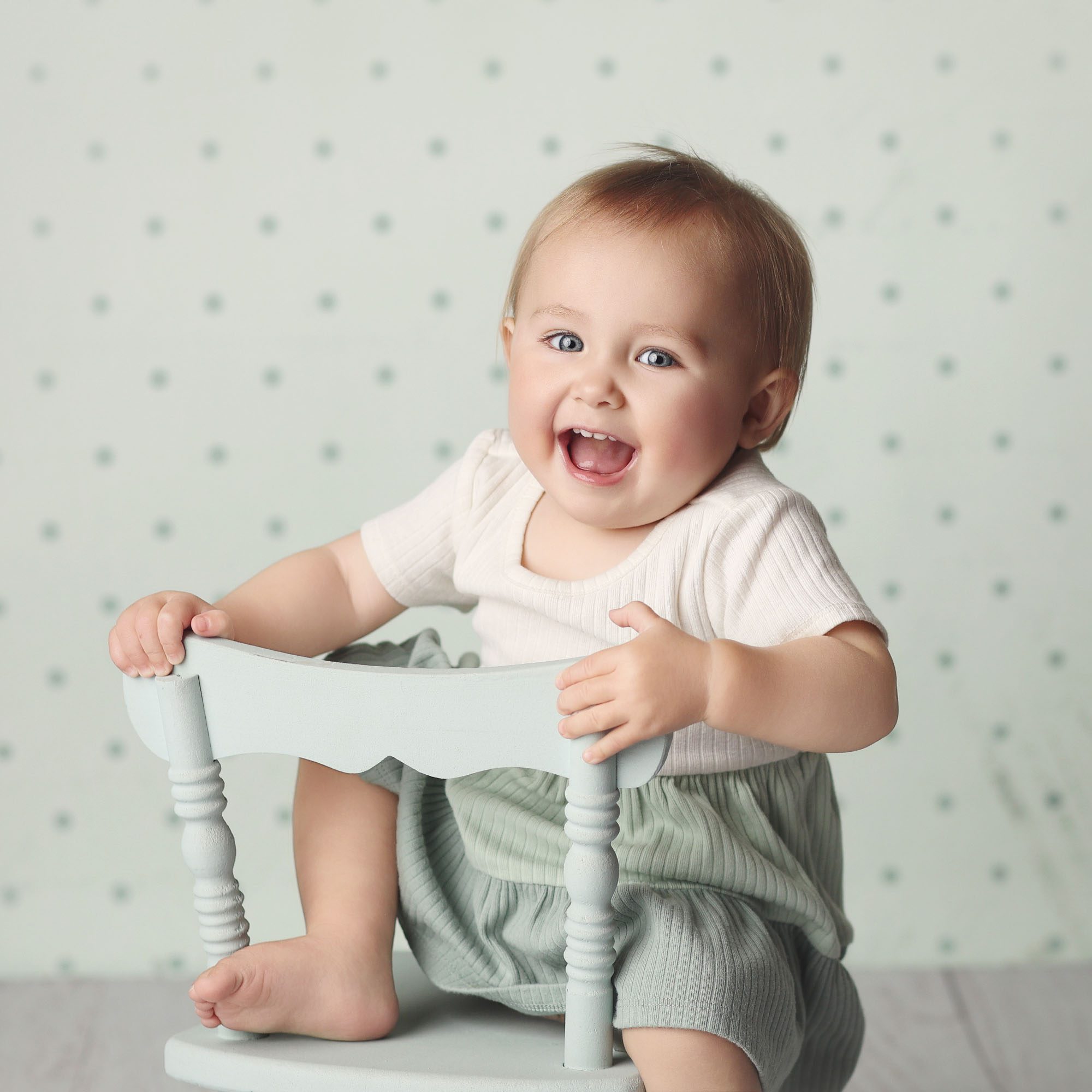 Baby girl sitter portrait on minit green chair with polka dot studio backdrop in Olathe Kansas