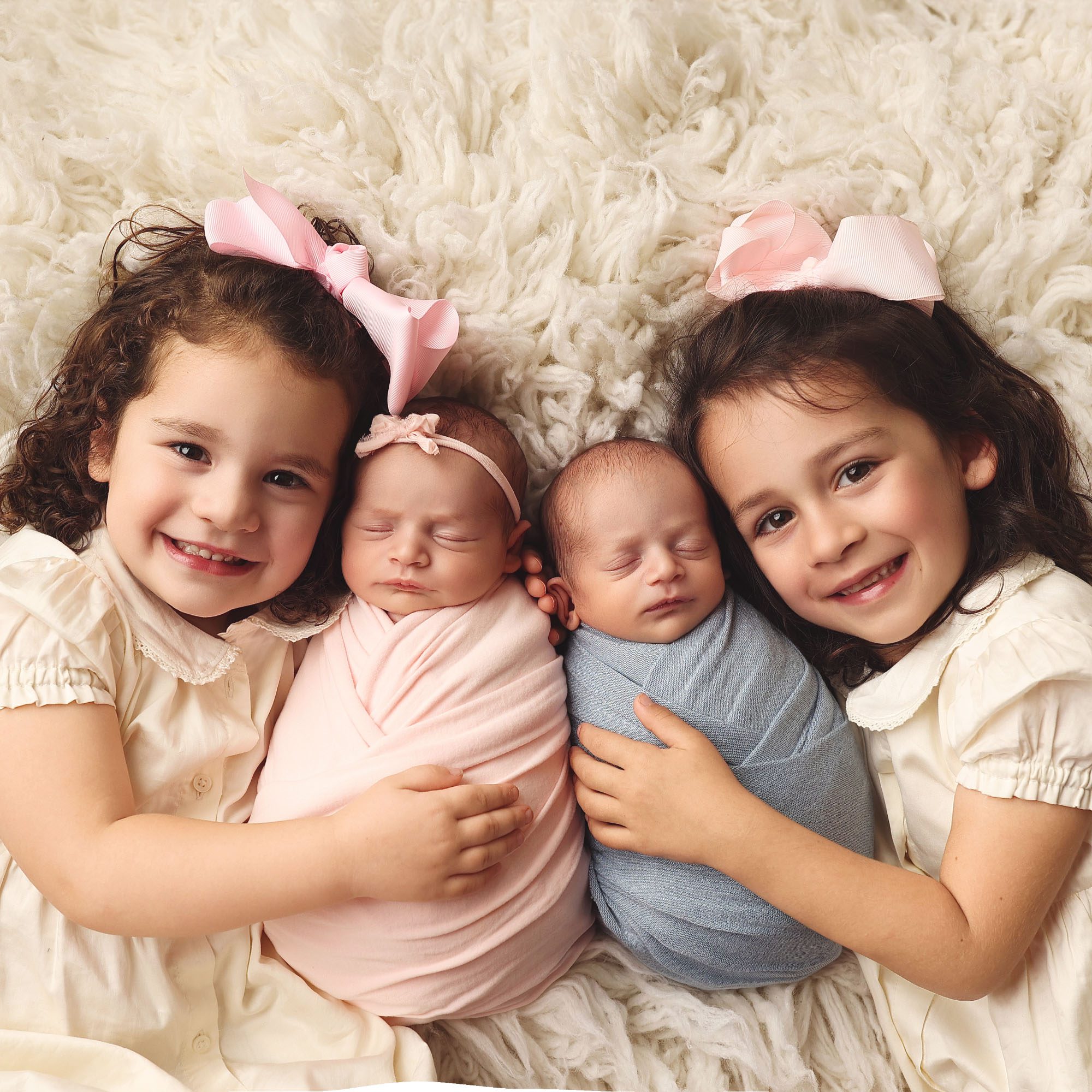 Overhead studio portrait of twin newborn babies with older sisters in Olathe Kansas
