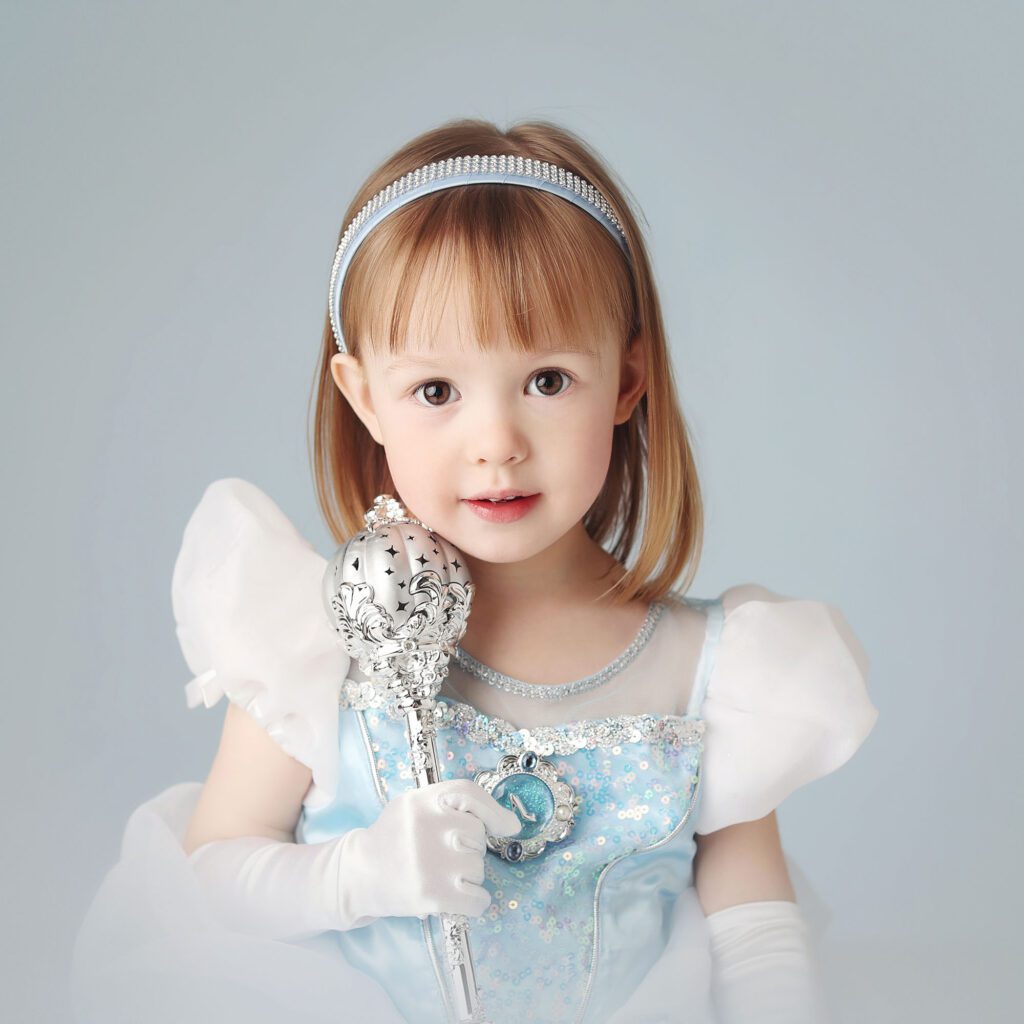 Little girl dressed as Cinderella holding a wand in a studio portrait