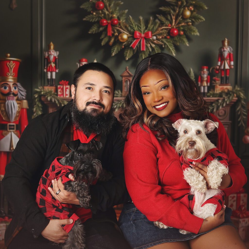 Young couple holdiing dogs in Christmas sweaters during a holiday photo session